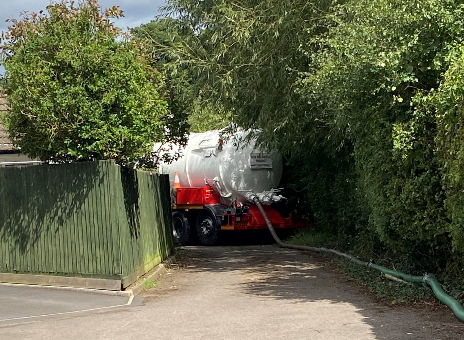 Vacuum tanker emptying a septic tank from a residential driveway